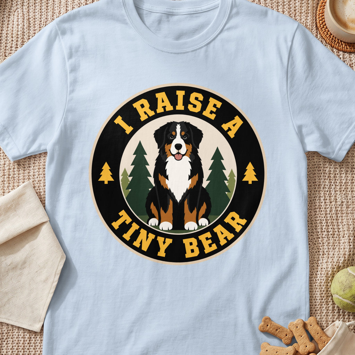 Bernese Mountain Dog sits in front of trees with text "I RAISE A TINY BEAR".