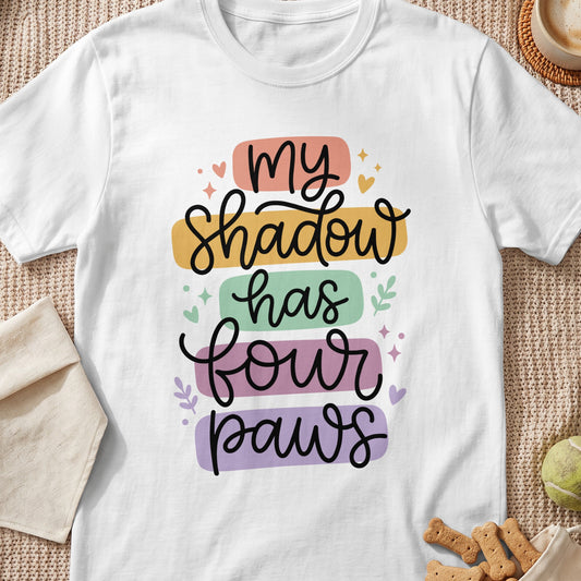 White t-shirt with text "my shadow has four paws" in colorful blocks.