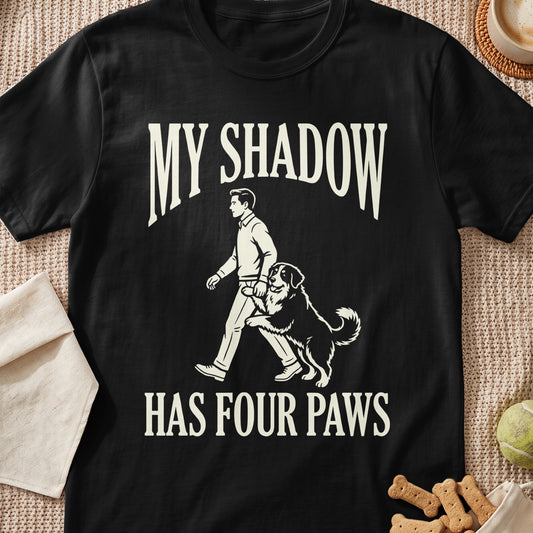 Black t-shirt with "MY SHADOW HAS FOUR PAWS" and a man walking with a dog.