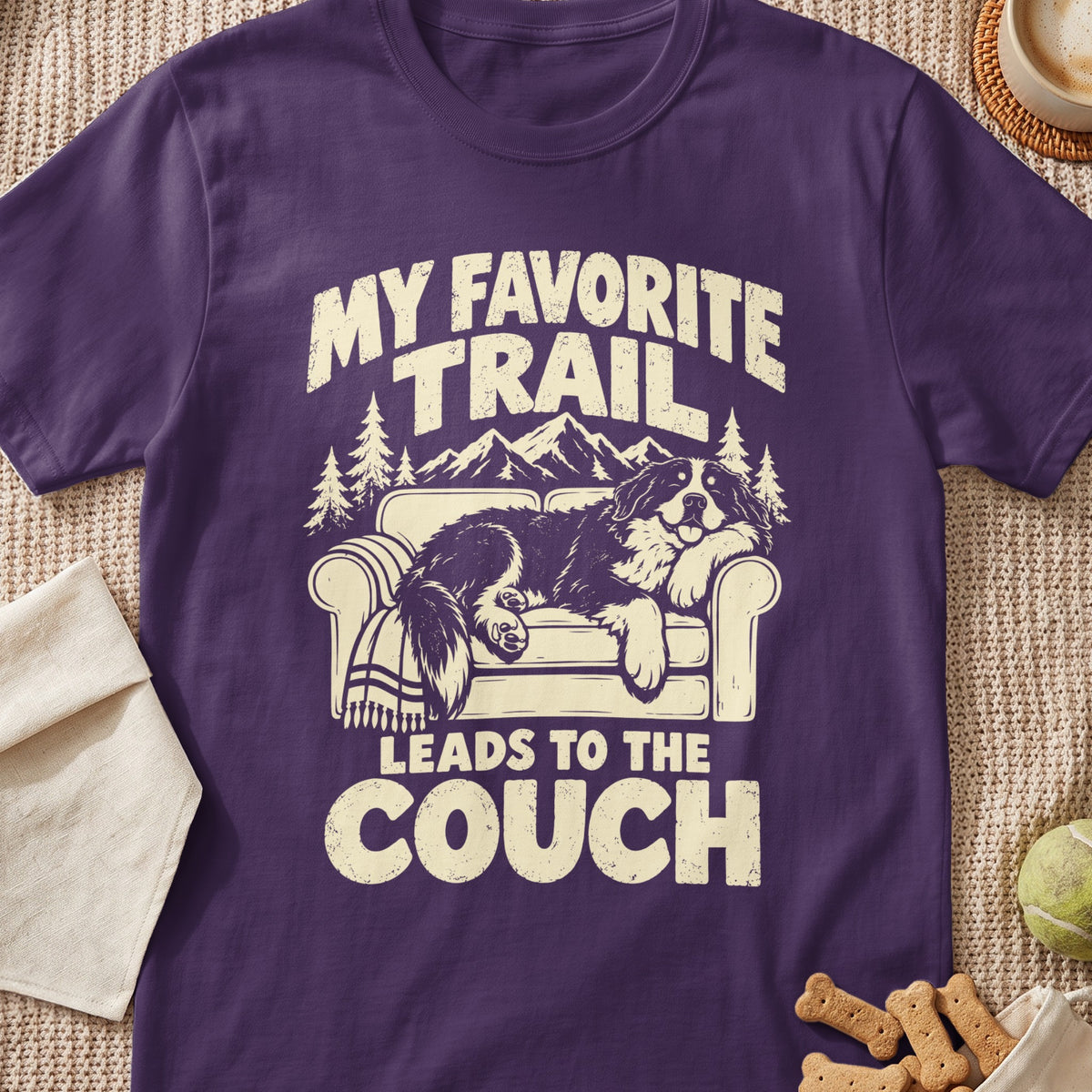 Purple t-shirt with text "MY FAVORITE TRAIL LEADS TO THE COUCH" and dog on couch graphic.