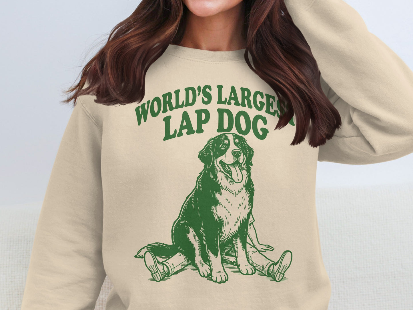 Cream crewneck sweatshirt with green illustration of a dog and text "WORLD'S LARGEST LAP DOG."