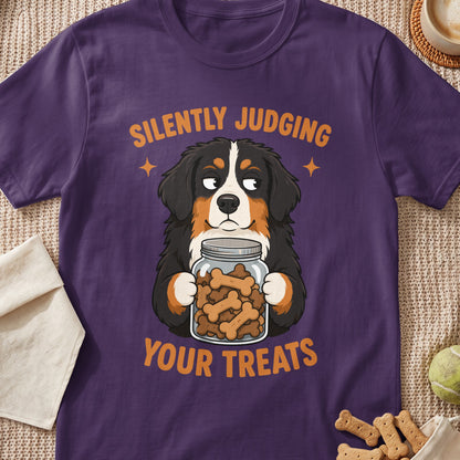 Bernese Mountain Dog holding a jar of bone-shaped treats, text says "Silently Judging Your Treats."