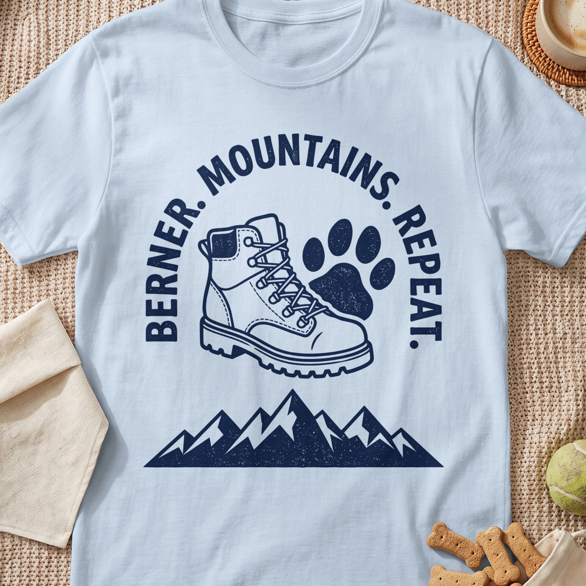 White t-shirt with graphic: "Berner. Mountains. Repeat." and hiking boot with paw print.