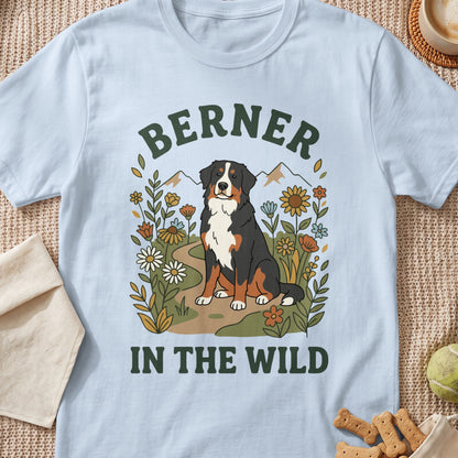 Bernese mountain dog sitting among flowers with mountains in background; "Berner in the Wild".