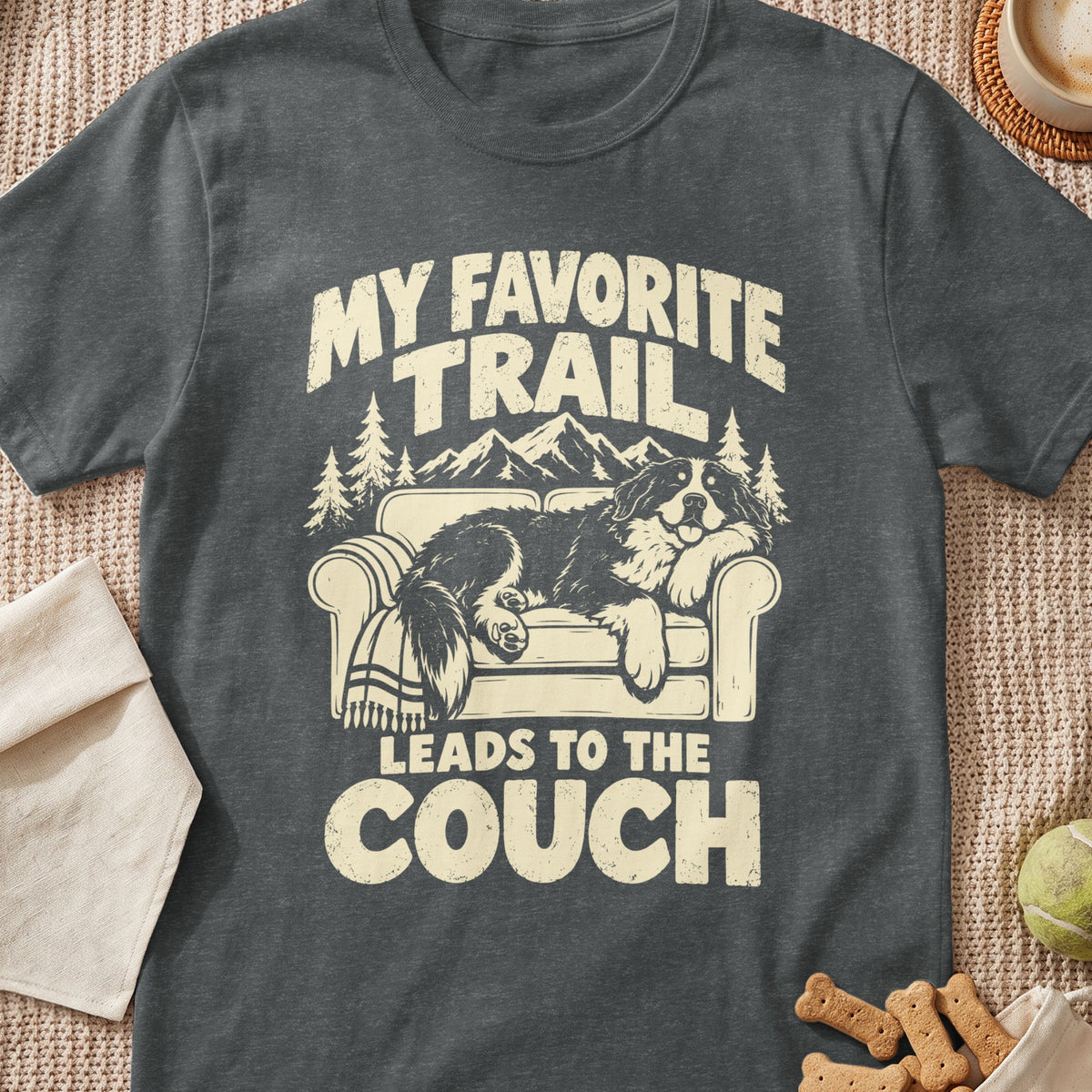 Dark grey t-shirt with a graphic of a dog lounging on a couch. Text reads, "MY FAVORITE TRAIL LEADS TO THE COUCH."