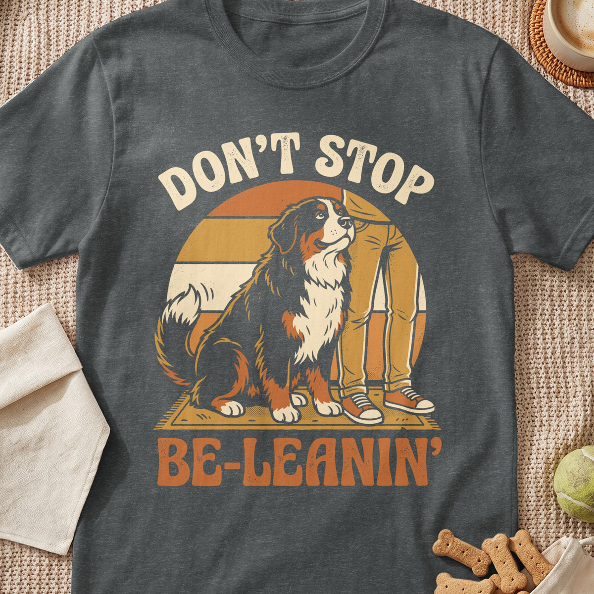 Bernese Mountain Dog sits by a person's legs with text "Don't Stop Be-Leaning".