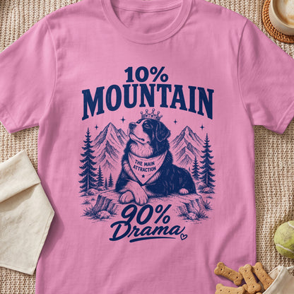Pink t-shirt with a blue graphic of a Bernese Mountain Dog wearing a crown and bandana amidst mountains.