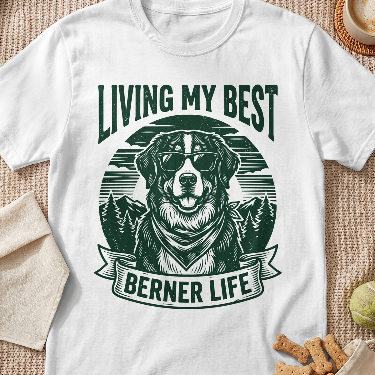 White t-shirt with green graphic of a Bernese Mountain Dog wearing sunglasses and bandana. Text says "LIVING MY BEST BERNER LIFE".