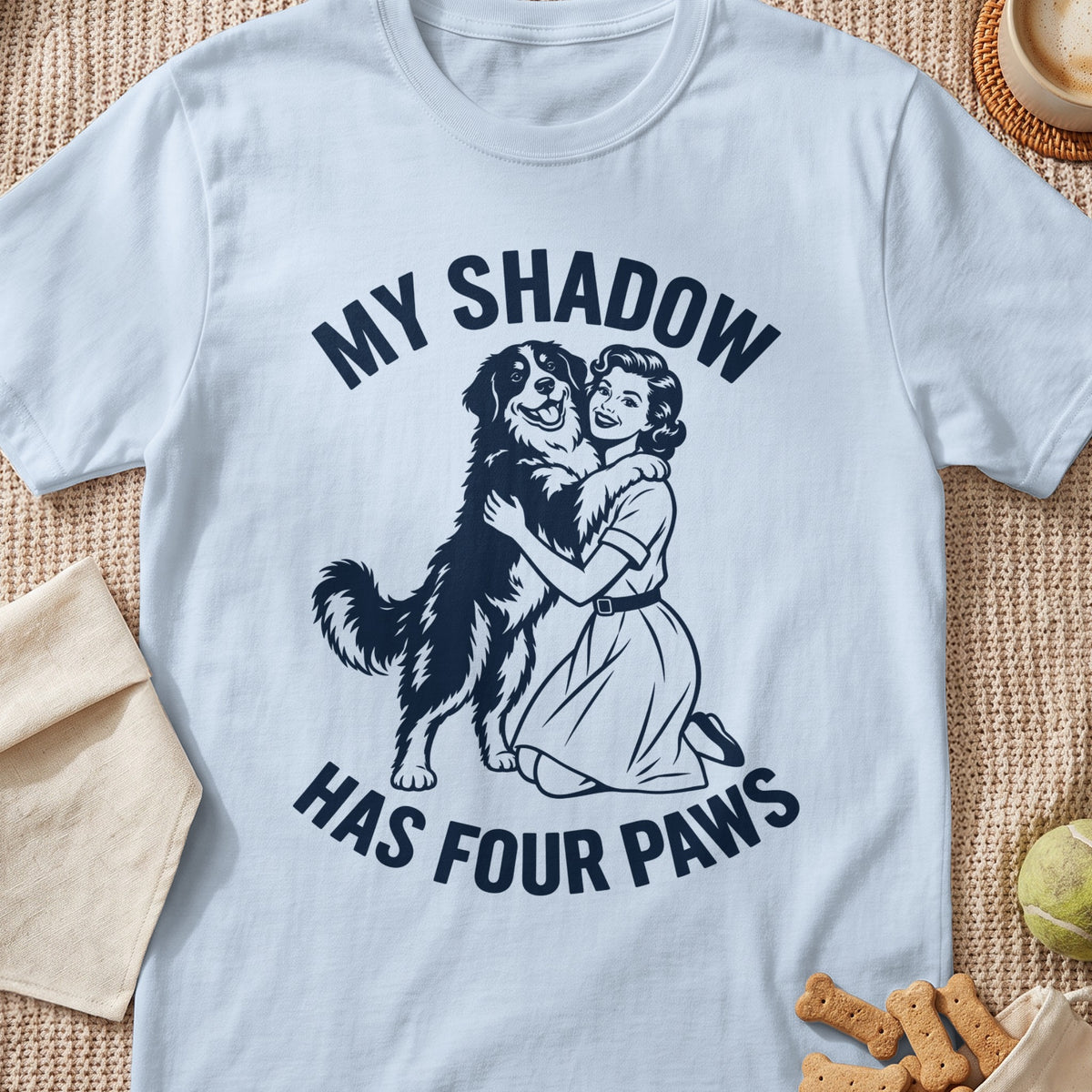 White t-shirt with a graphic of a woman hugging a dog and text "MY SHADOW HAS FOUR PAWS".