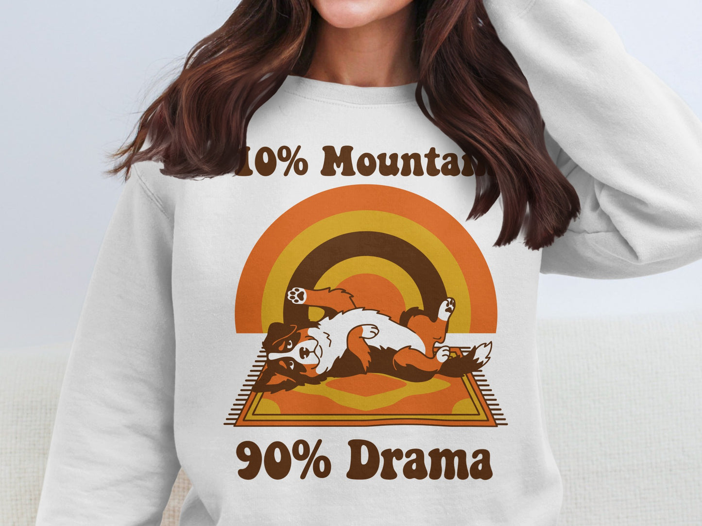 White sweatshirt with retro graphic of dog on rug and text "10% Mountain 90% Drama".