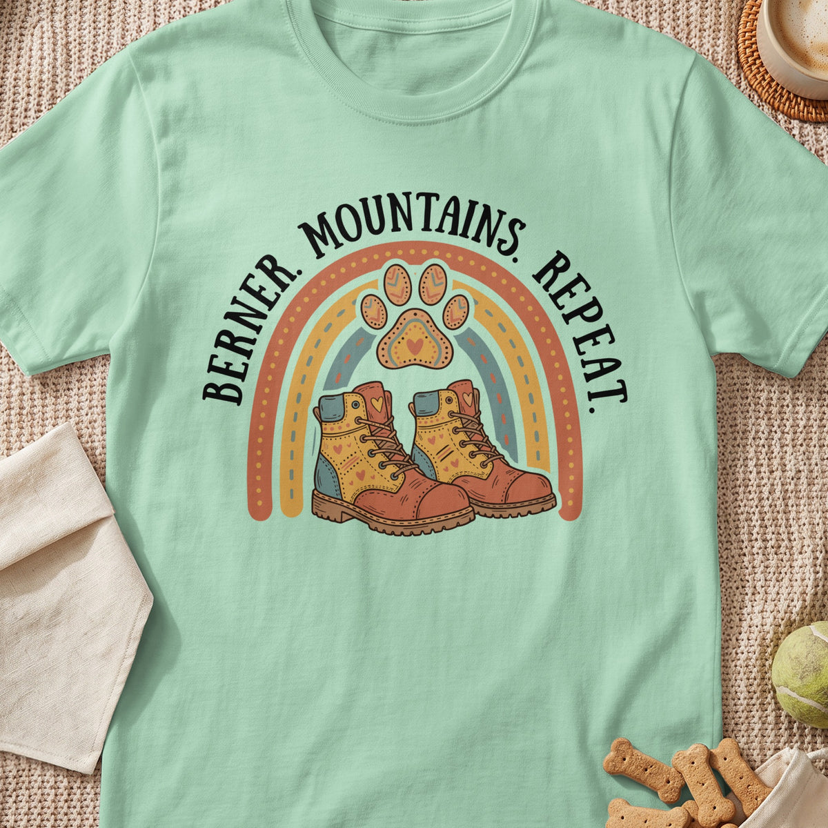 Mint green t-shirt with rainbow, paw print, and hiking boots graphic reading "Berner. Mountains. Repeat."
