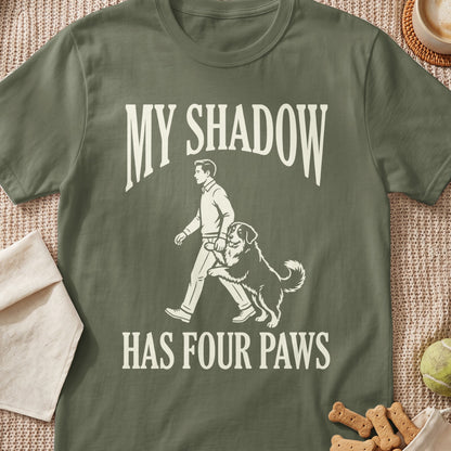 T-shirt graphic with text "MY SHADOW HAS FOUR PAWS" and man walking dog.