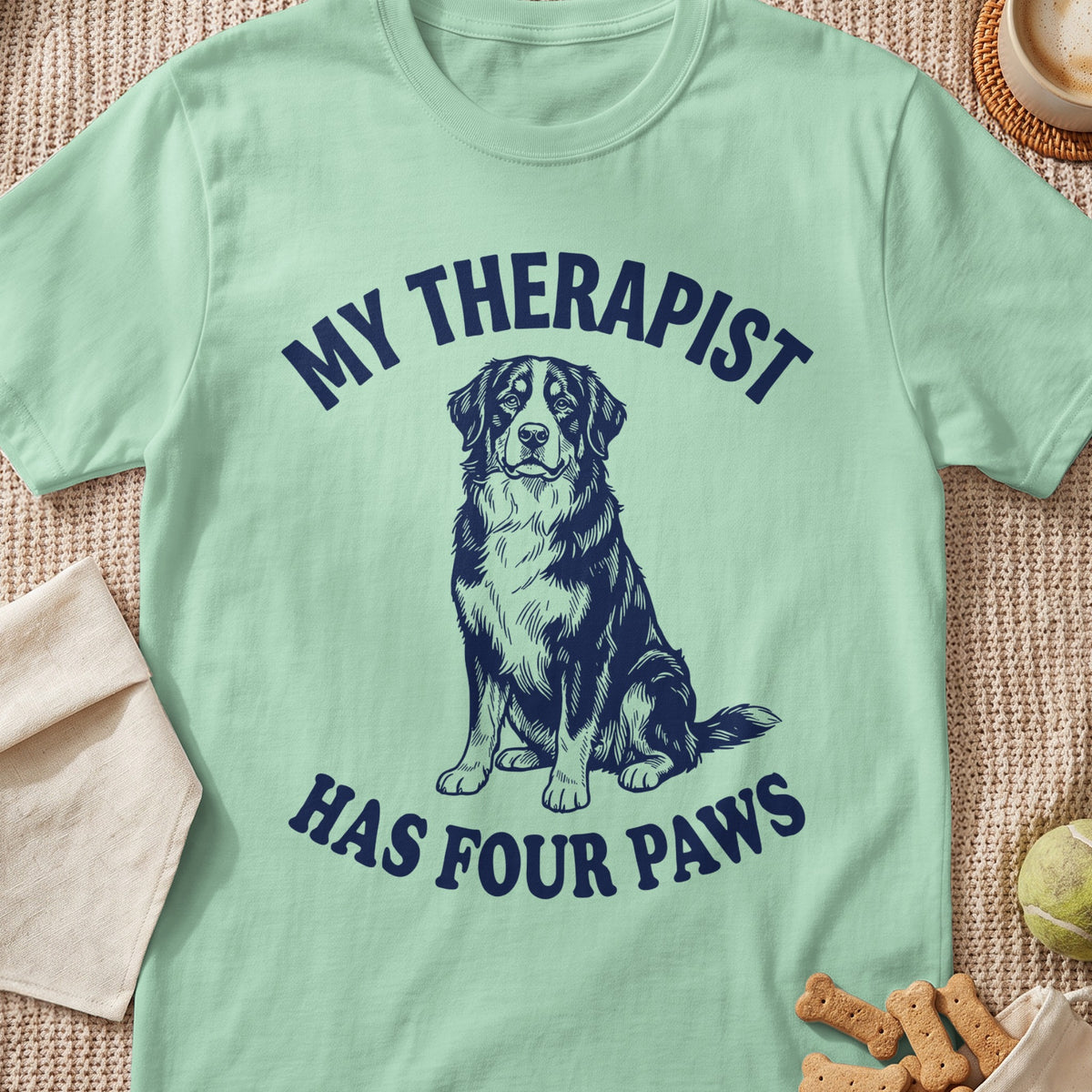 Light green t-shirt with dark blue text and dog graphic. Text reads "MY THERAPIST HAS FOUR PAWS".