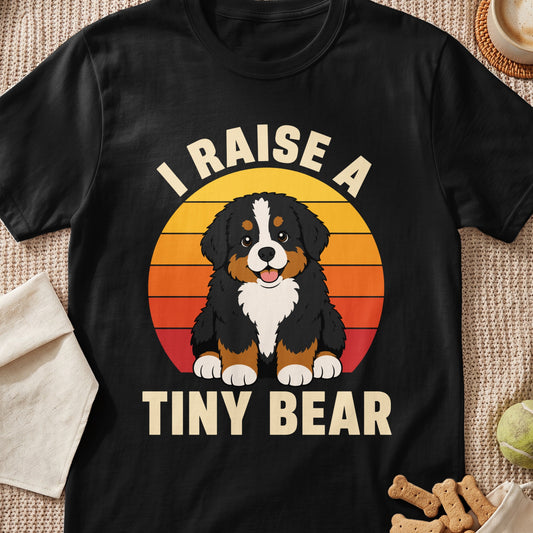 Bernese Mountain Dog puppy with text "I RAISE A TINY BEAR" on black t-shirt.