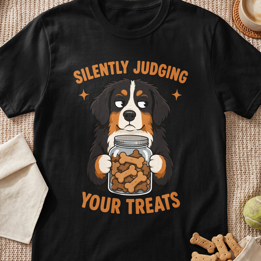 Black t-shirt featuring an illustrated Bernese Mountain Dog holding a treat jar with text reading silently judging your treats.