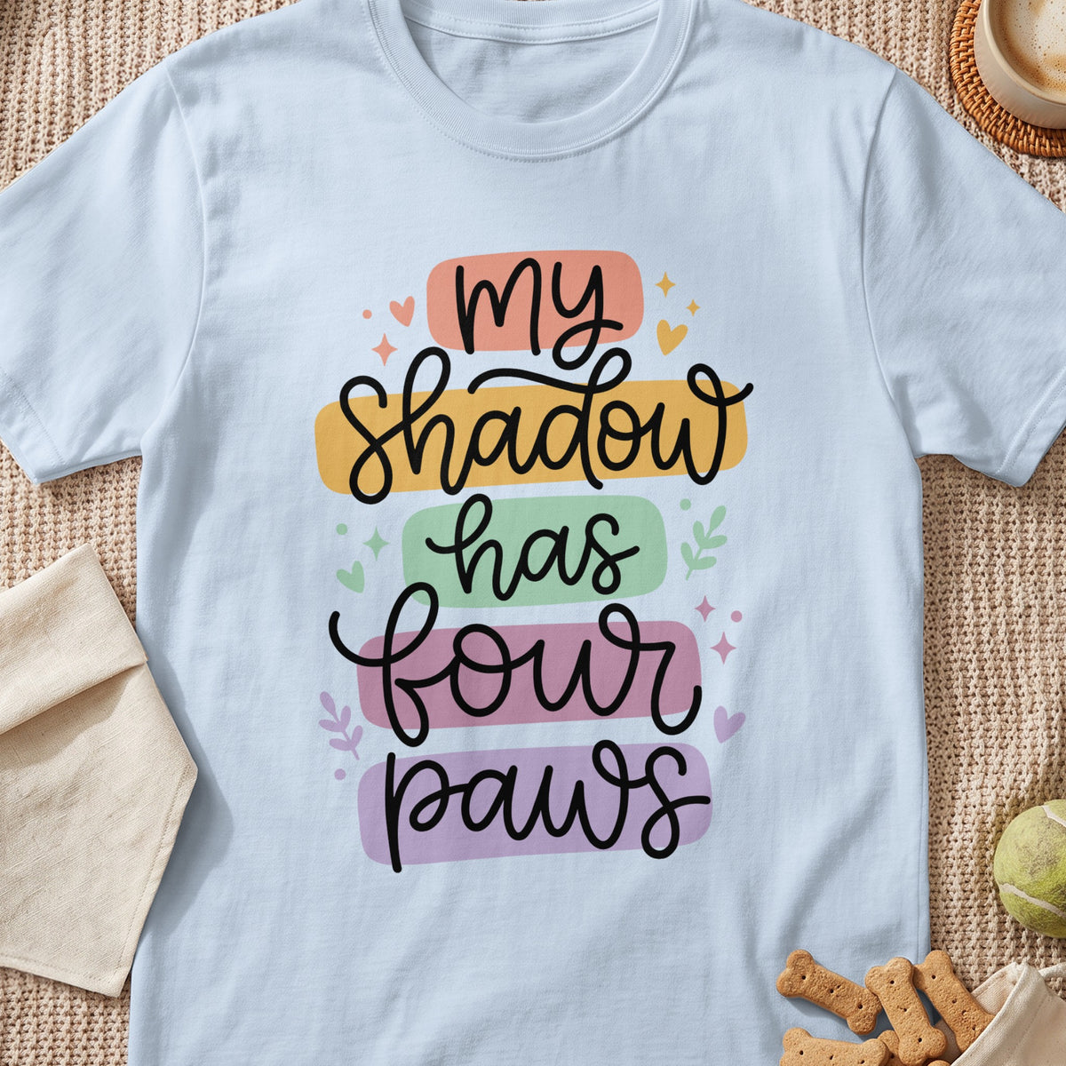 Light blue t-shirt with "My Shadow Has Four Paws" text in colorful blocks.