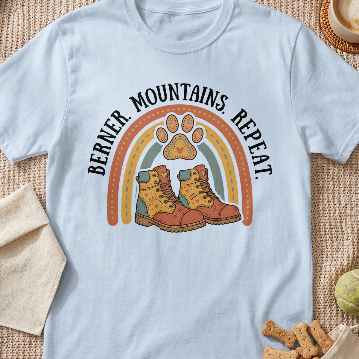 Light blue t-shirt with rainbow, paw print, hiking boots, and "Berner. Mountains. Repeat." text.