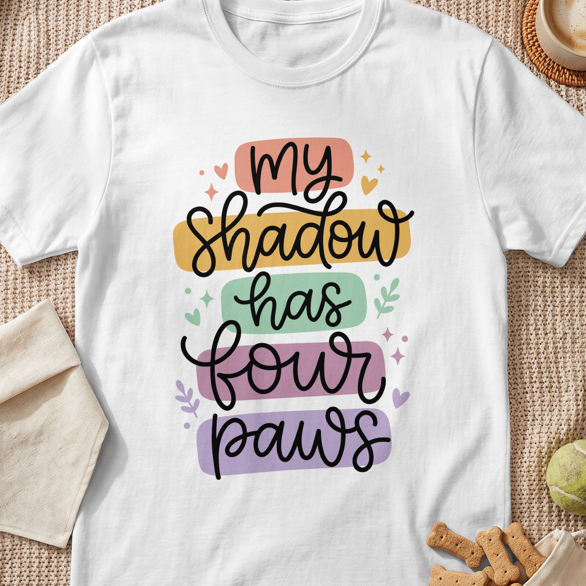 White t-shirt with text "my shadow has four paws" in colorful blocks.