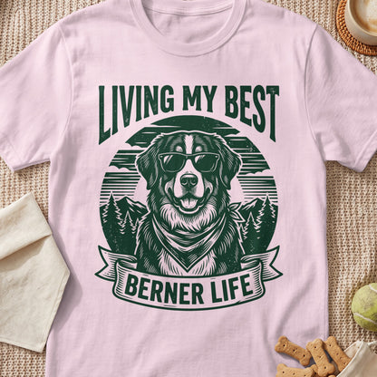 Pink t-shirt with a green graphic of a dog in sunglasses saying "LIVING MY BEST BERNER LIFE".