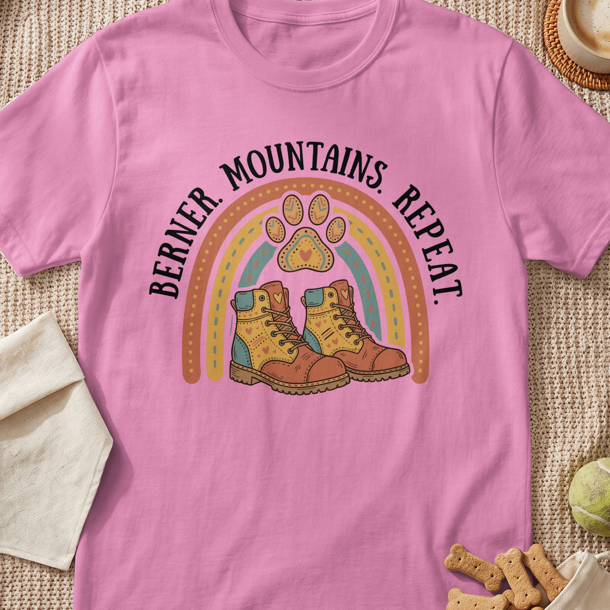 Pink t-shirt with "Berner. Mountains. Repeat." text, rainbow, and hiking boots graphic.