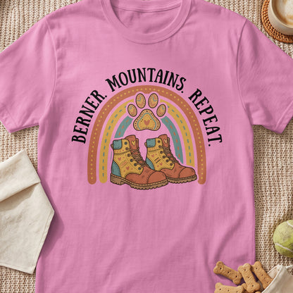 Pink t-shirt with "Berner. Mountains. Repeat." text, rainbow, and hiking boots graphic.