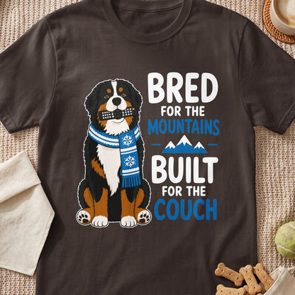 Bernese Mountain Dog wearing scarf, holding remote, text: Bred for mountains, built for couch.