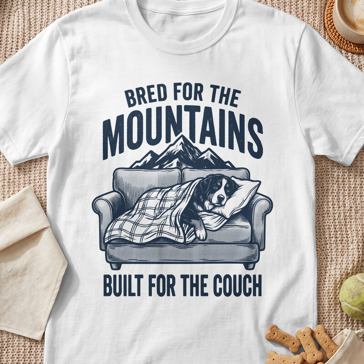 Bernese Mountain Dog sleeping on couch under blanket, text reads "Bred for the Mountains, Built for the Couch."