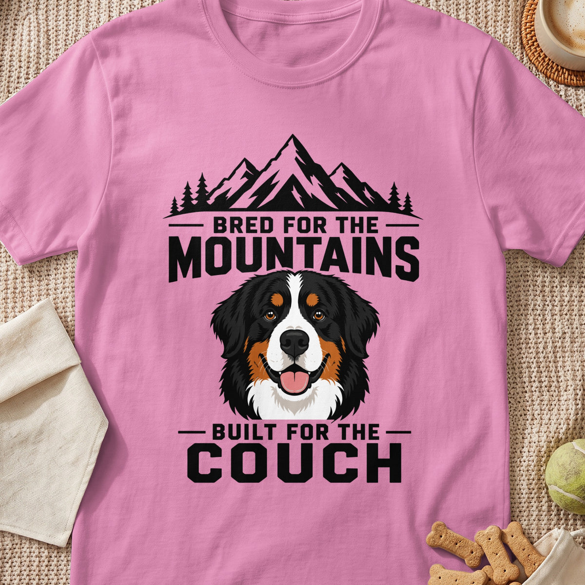 Pink t-shirt with mountains, trees, Bernese Mountain Dog, and text "Bred for the Mountains Built for the Couch".