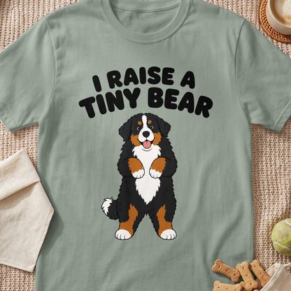 Green t-shirt with black text "I RAISE A TINY BEAR" and cartoon Bernese Mountain Dog.