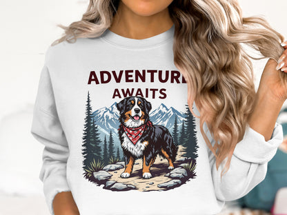 Bernese Mountain Dog wearing bandana with "ADVENTURE AWAITS" over mountain landscape.