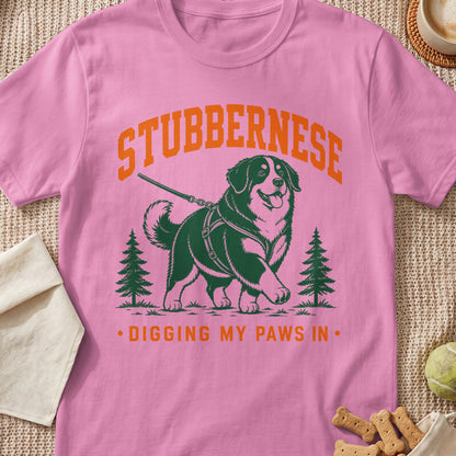 Pink t-shirt with graphic of a dog, trees, and text "STUBBERNESE. DIGGING MY PAWS IN."