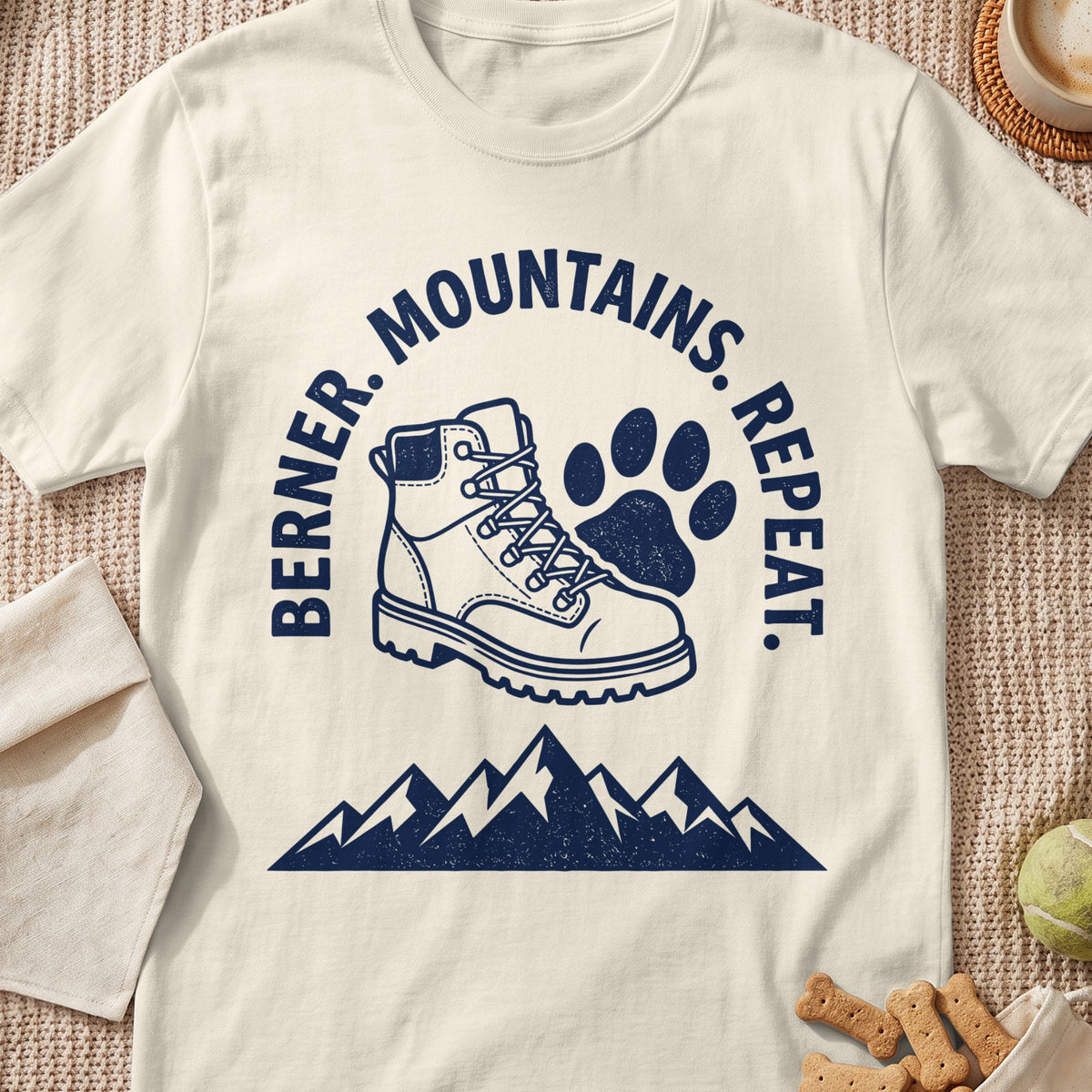 Berner. Mountains. Repeat. graphic on cream t-shirt with hiking boot and paw print.