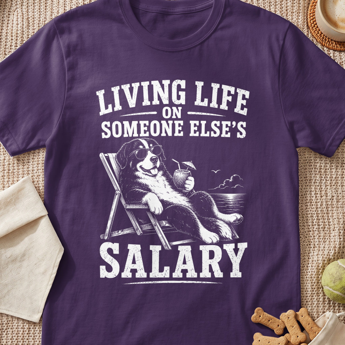 Bernese Mountain Dog relaxing on beach with text "Living Life On Someone Else's Salary".