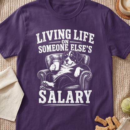 Bernese Mountain Dog wearing sunglasses, holding coffee and sitting on a couch, text reads "Living Life On Someone Else's Salary".