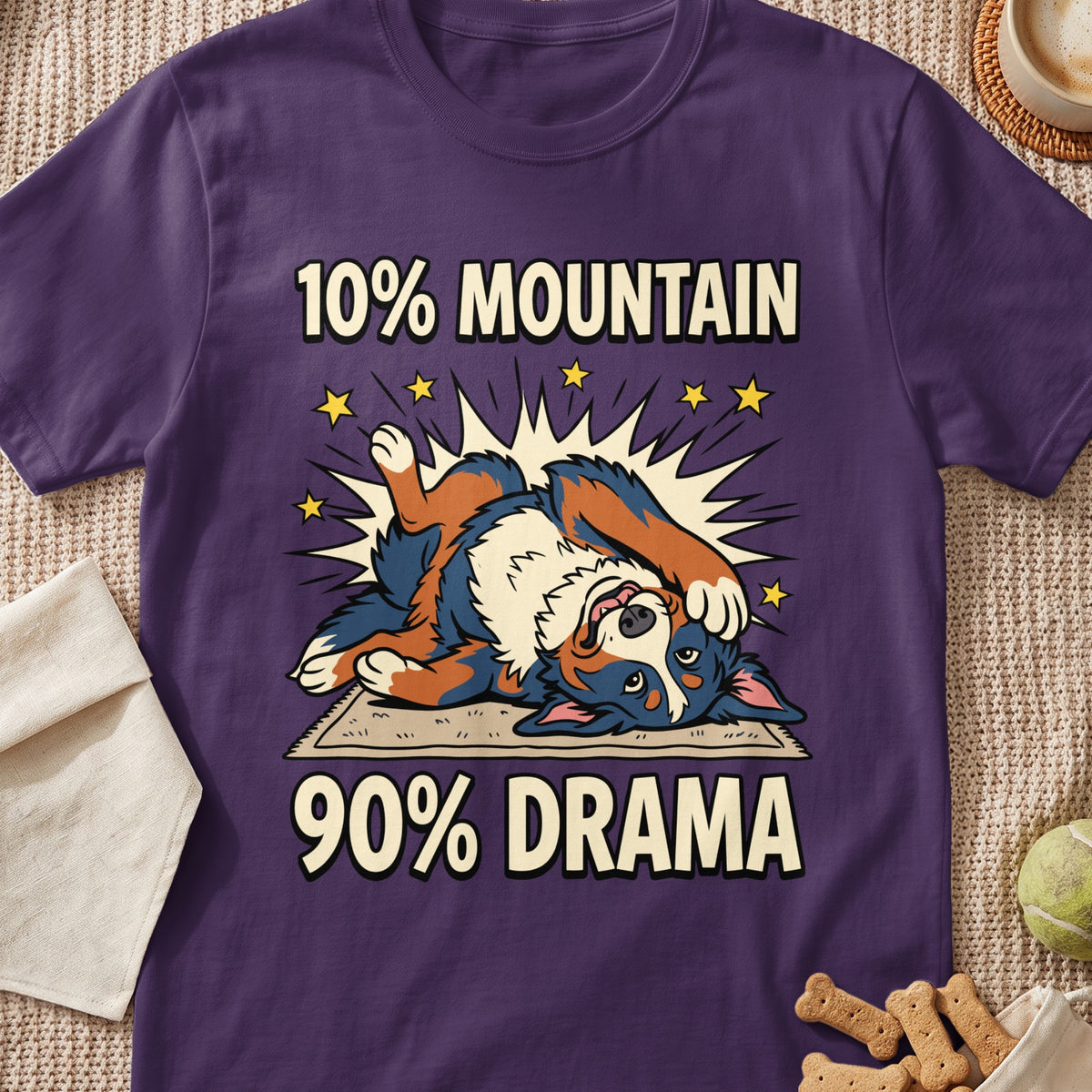 A purple t-shirt featuring a graphic of a dog lying on its back with the text 10% Mountain 90% Drama.