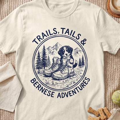 Bernese puppy in hiking boots with mountains and text "Trails, Tails & Bernese Adventures".