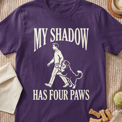 Purple t-shirt with graphic of person walking dog and text "MY SHADOW HAS FOUR PAWS".