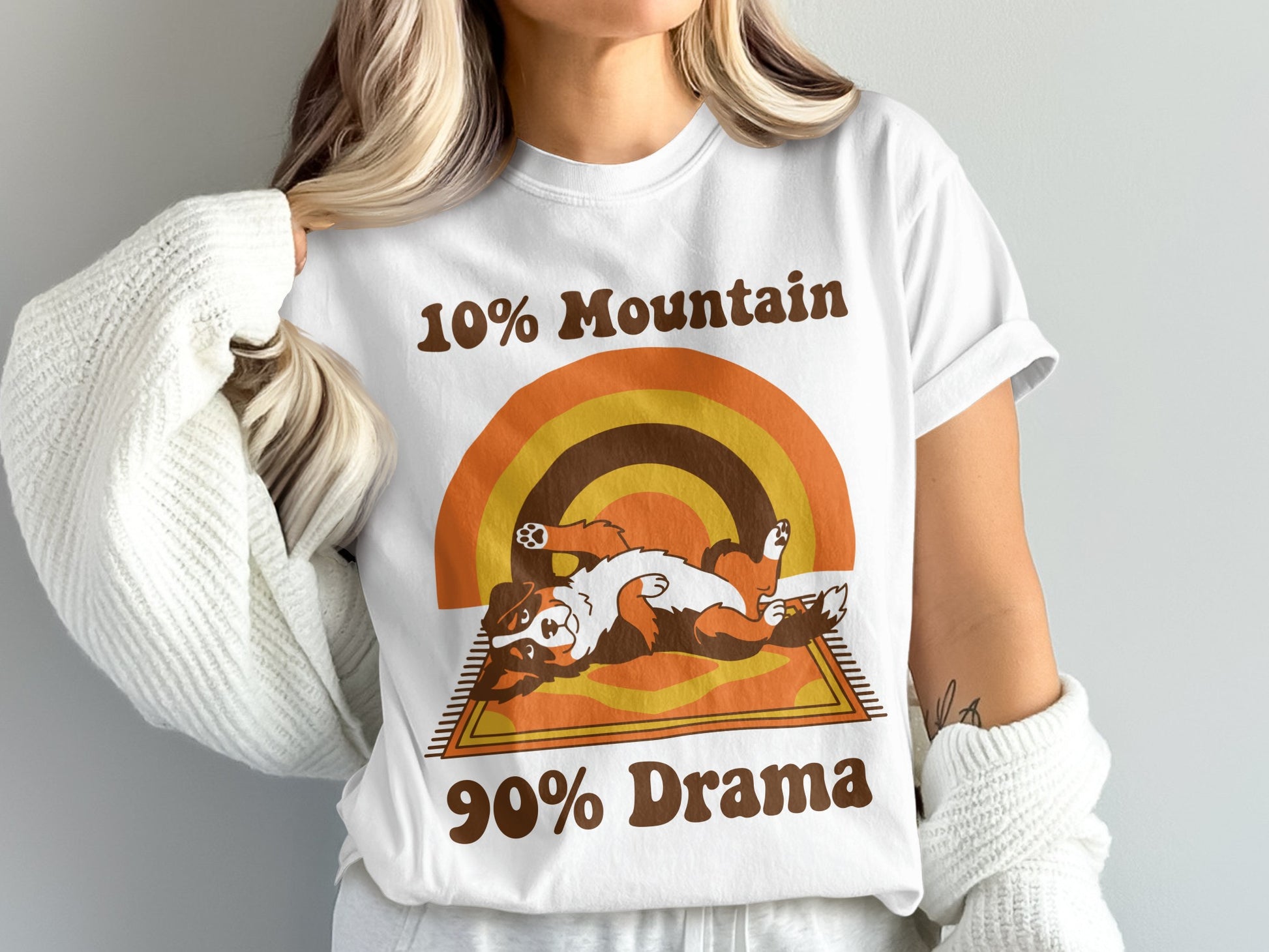White t-shirt with retro rainbow graphic, a dog, and text "10% Mountain 90% Drama".