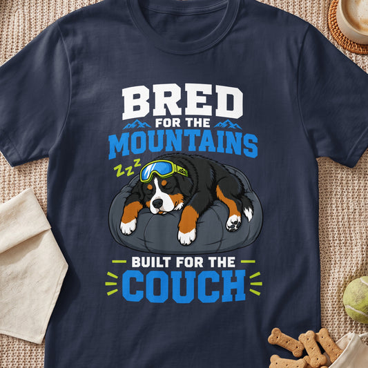 Bernese Mountain Dog wearing goggles sleeps on a pillow with text "Bred for the Mountains Built for the Couch".