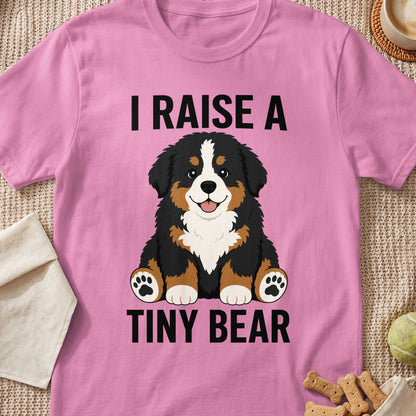Pink t-shirt with text "I RAISE A TINY BEAR" and a Bernese Mountain Dog puppy graphic.