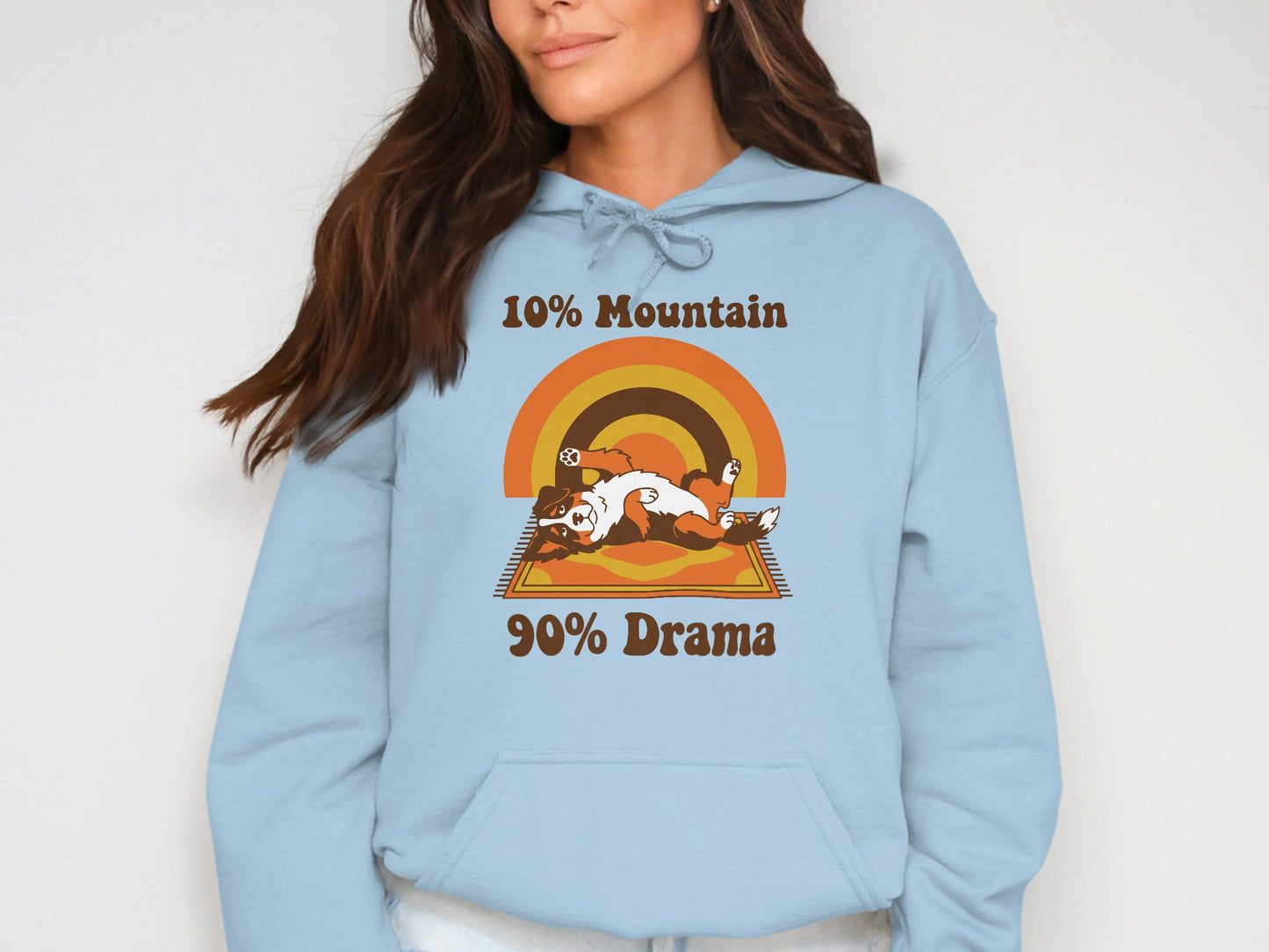 Light blue hoodie with "10% Mountain 90% Drama" text and a dog on a rug.