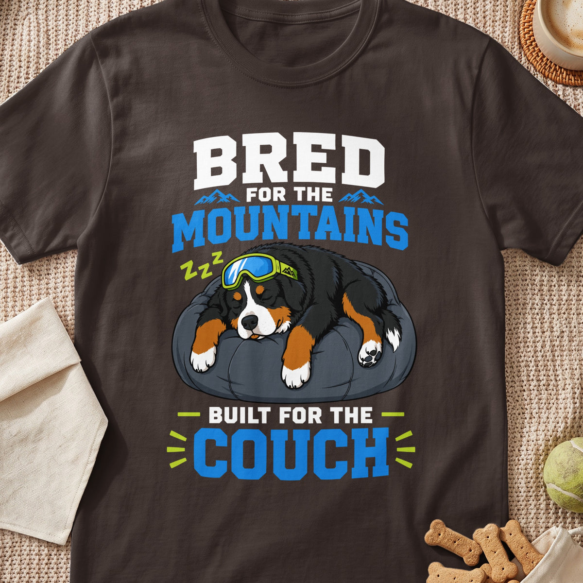 Bernese Mountain Dog with goggles sleeping on a cushion, text "Bred for the Mountains, Built for the Couch".