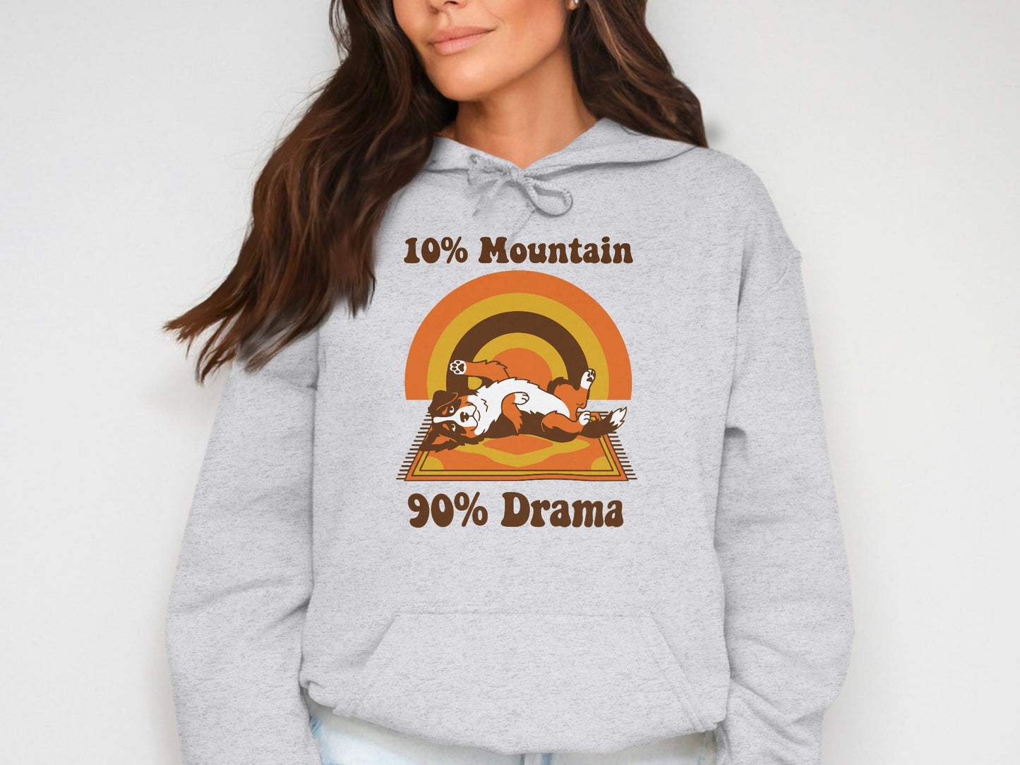 Grey hoodie with "10% Mountain 90% Drama" text and stylized dog on a rug.