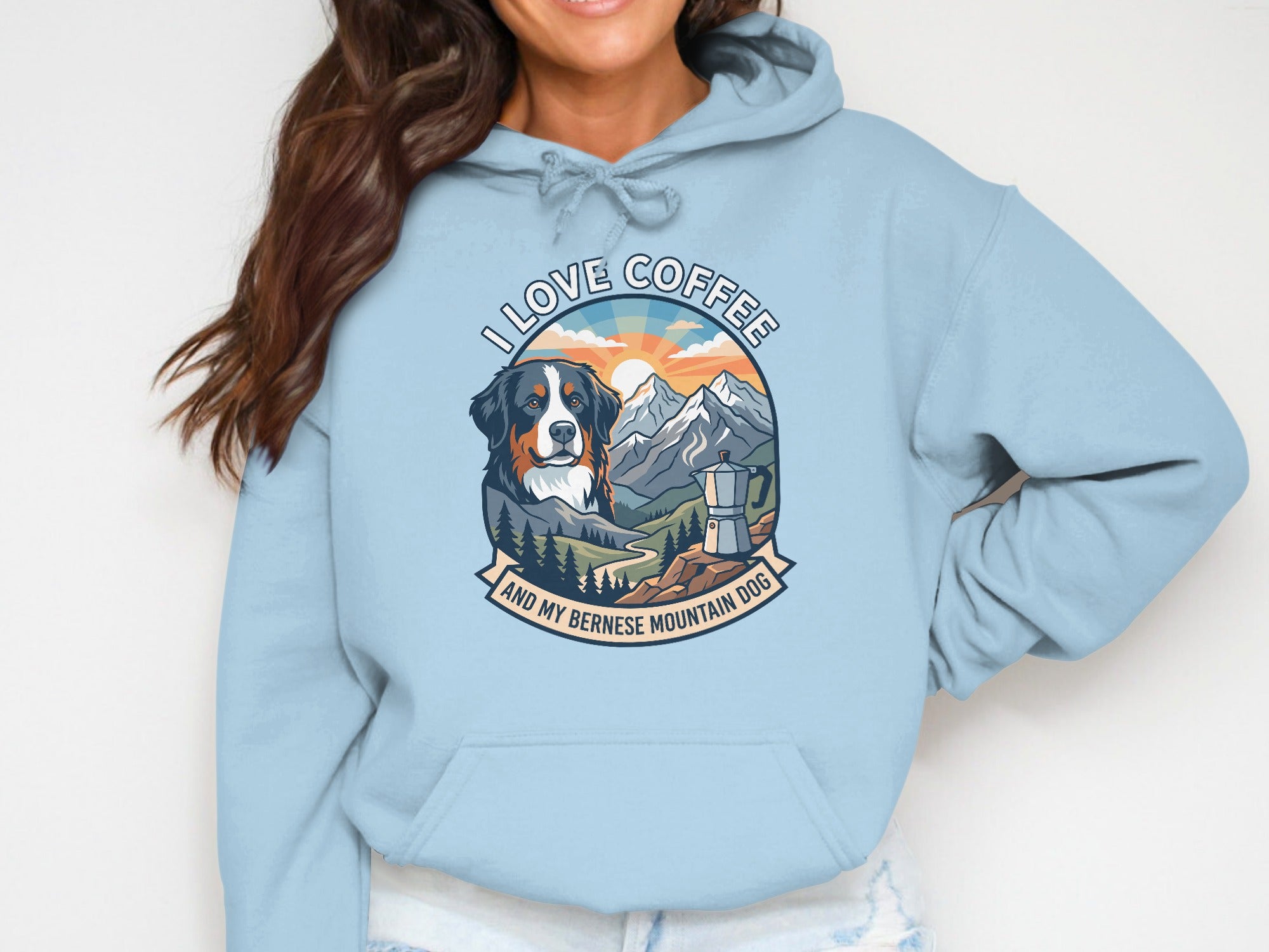 Light blue hoodie with a graphic of a Bernese Mountain dog, mountains, and the text "I LOVE COFFEE AND MY BERNESE MOUNTAIN DOG".
