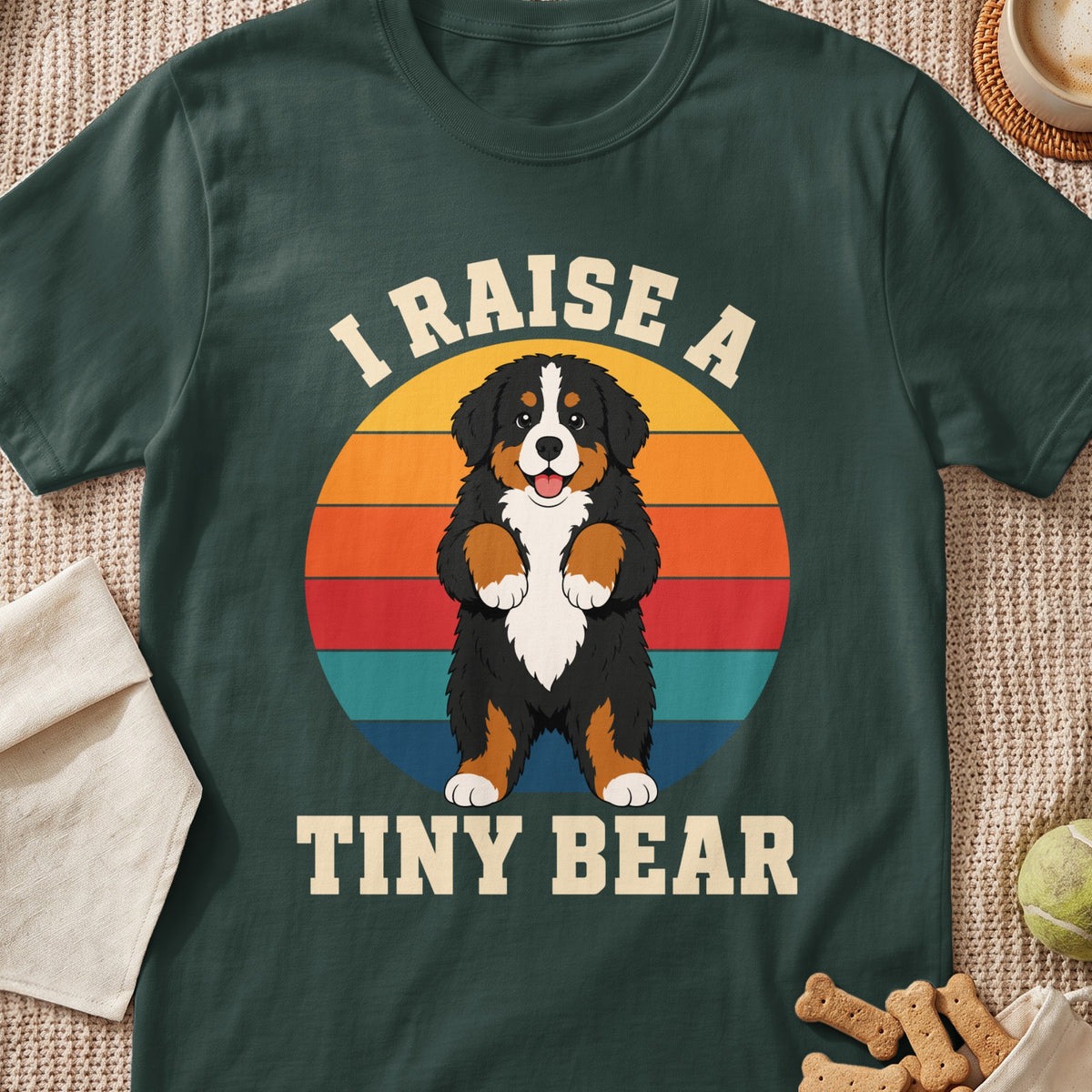 Bernese Mountain Dog illustration with text "I RAISE A TINY BEAR" on a dark green t-shirt.