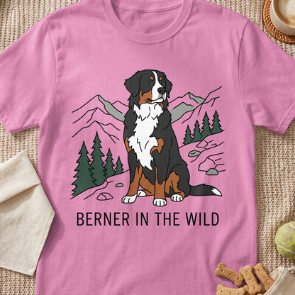 Pink t-shirt with a drawing of a Bernese Mountain Dog sitting in a mountain landscape, text reads "BERNER IN THE WILD".