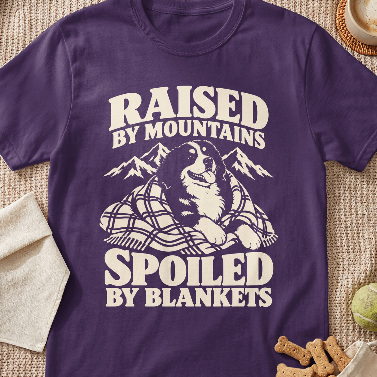Purple t-shirt with text "RAISED BY MOUNTAINS SPOILED BY BLANKETS" and dog design.