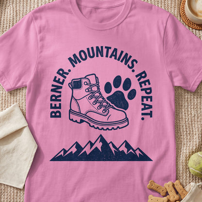 Pink t-shirt with "Berner. Mountains. Repeat." text, a hiking boot, and paw print.
