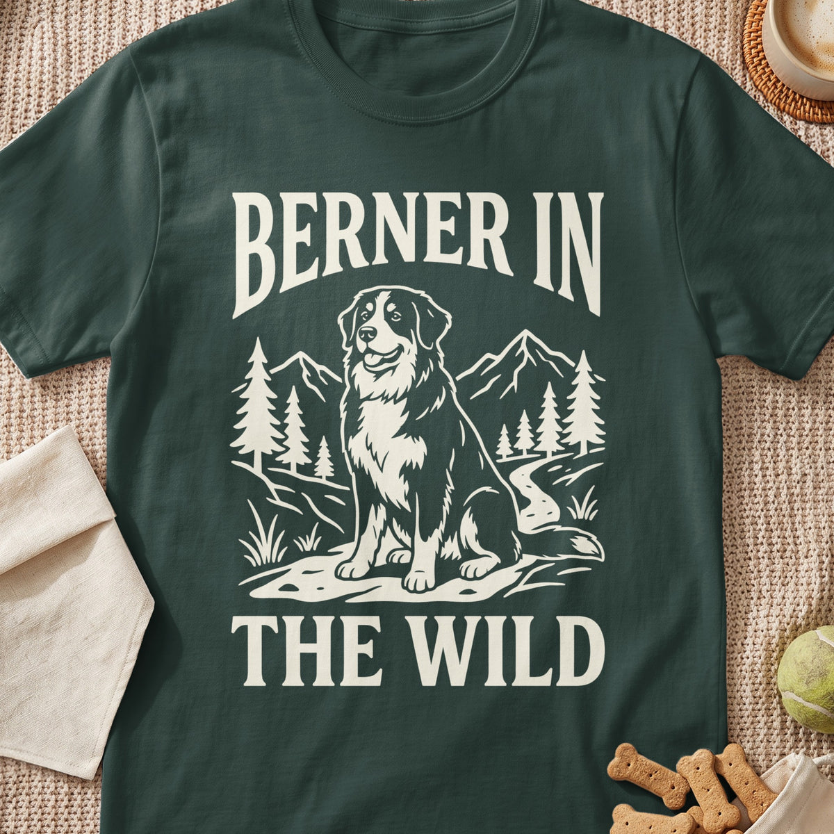 Berner in the Wild graphic on a dark green t-shirt featuring a dog and mountains.