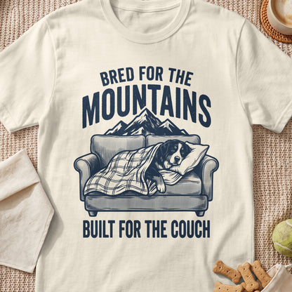 Dog on couch under blanket with text "Bred for the Mountains, Built for the Couch."